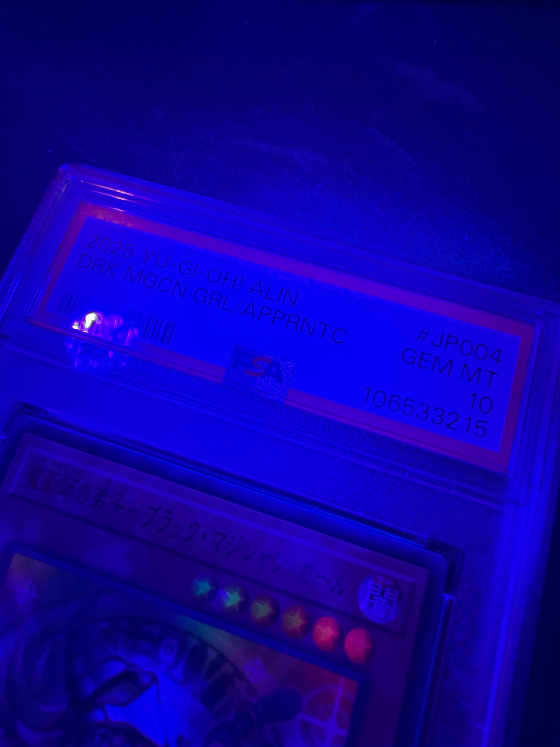 black light photo of 2025 YU-GI-OH! JAPANESE ALIN-ALLIANCE INSIGHT #JP004 DRK MGCN GRL/APPRNTC PSA 10 #106533215